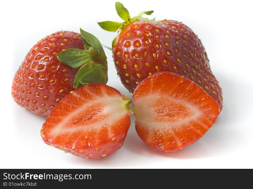 Two ripe strawberries and two segments of a strawberry. A photo close up.