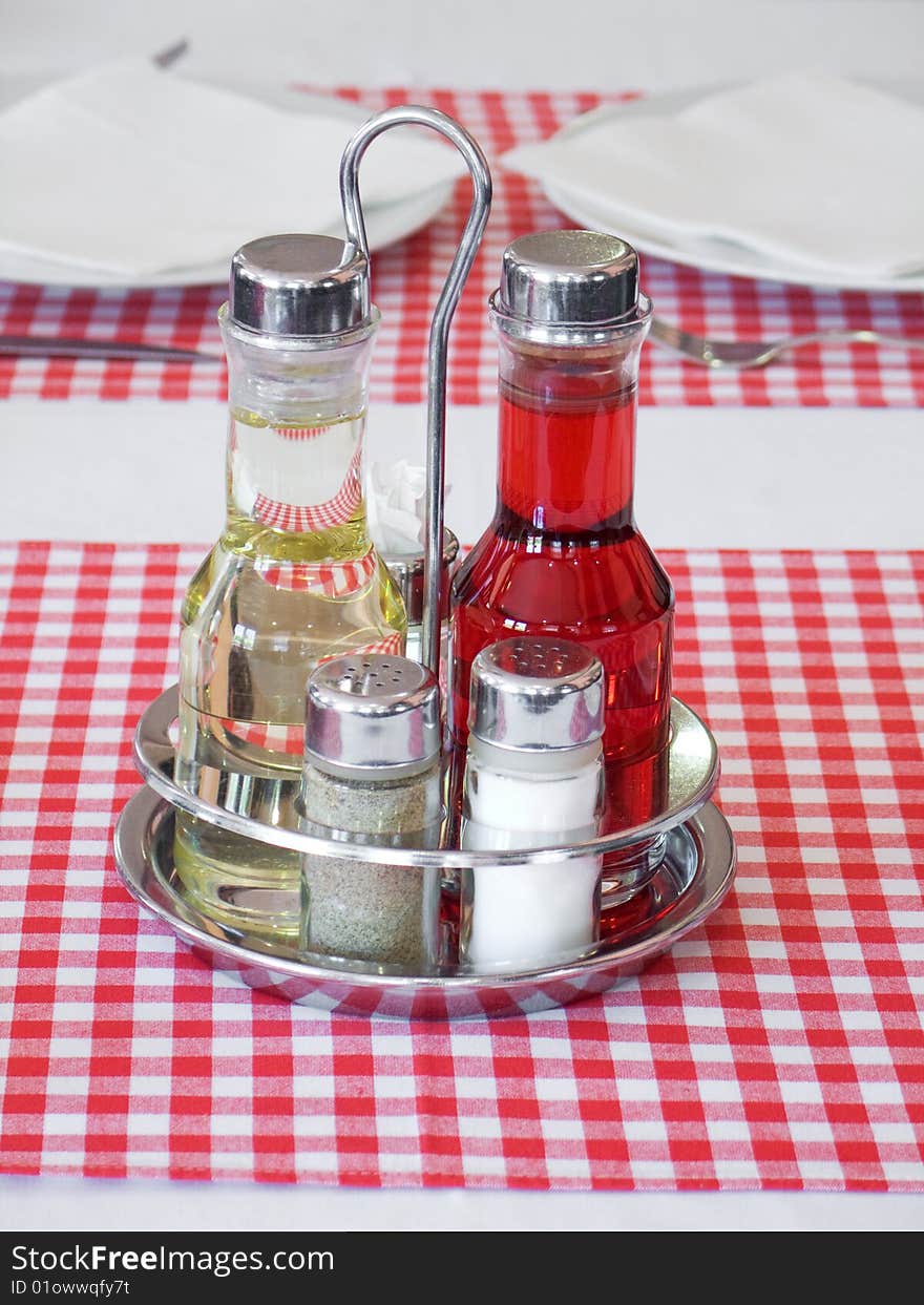 Plait with silverware and spices on table with red checked tablecloth. Plait with silverware and spices on table with red checked tablecloth