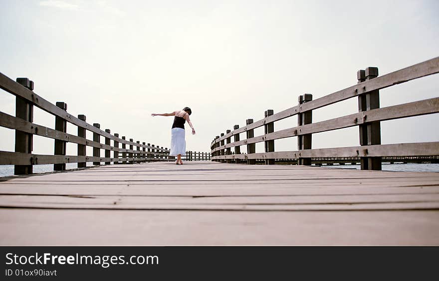 Girl balances along empty pier