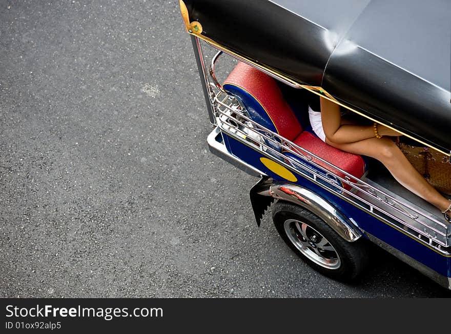 A tourist travels through the busy streets of Bangkok, Thailand in a tuk tuk. stopped at a traffic light she waits in the polluted city while clutching her bag. A tourist travels through the busy streets of Bangkok, Thailand in a tuk tuk. stopped at a traffic light she waits in the polluted city while clutching her bag.