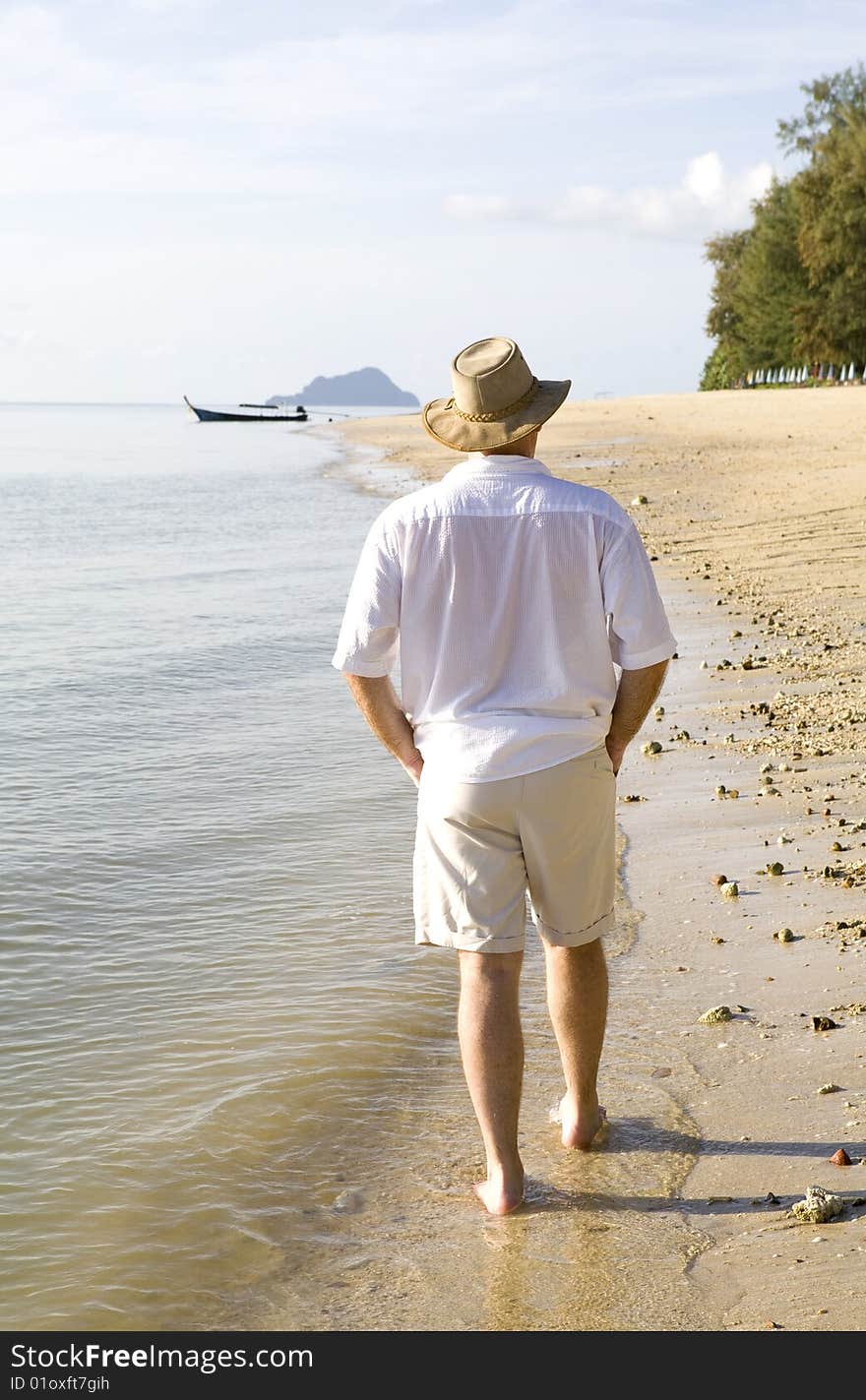 Handsome man strolling along a beautiful beach on an island. Handsome man strolling along a beautiful beach on an island