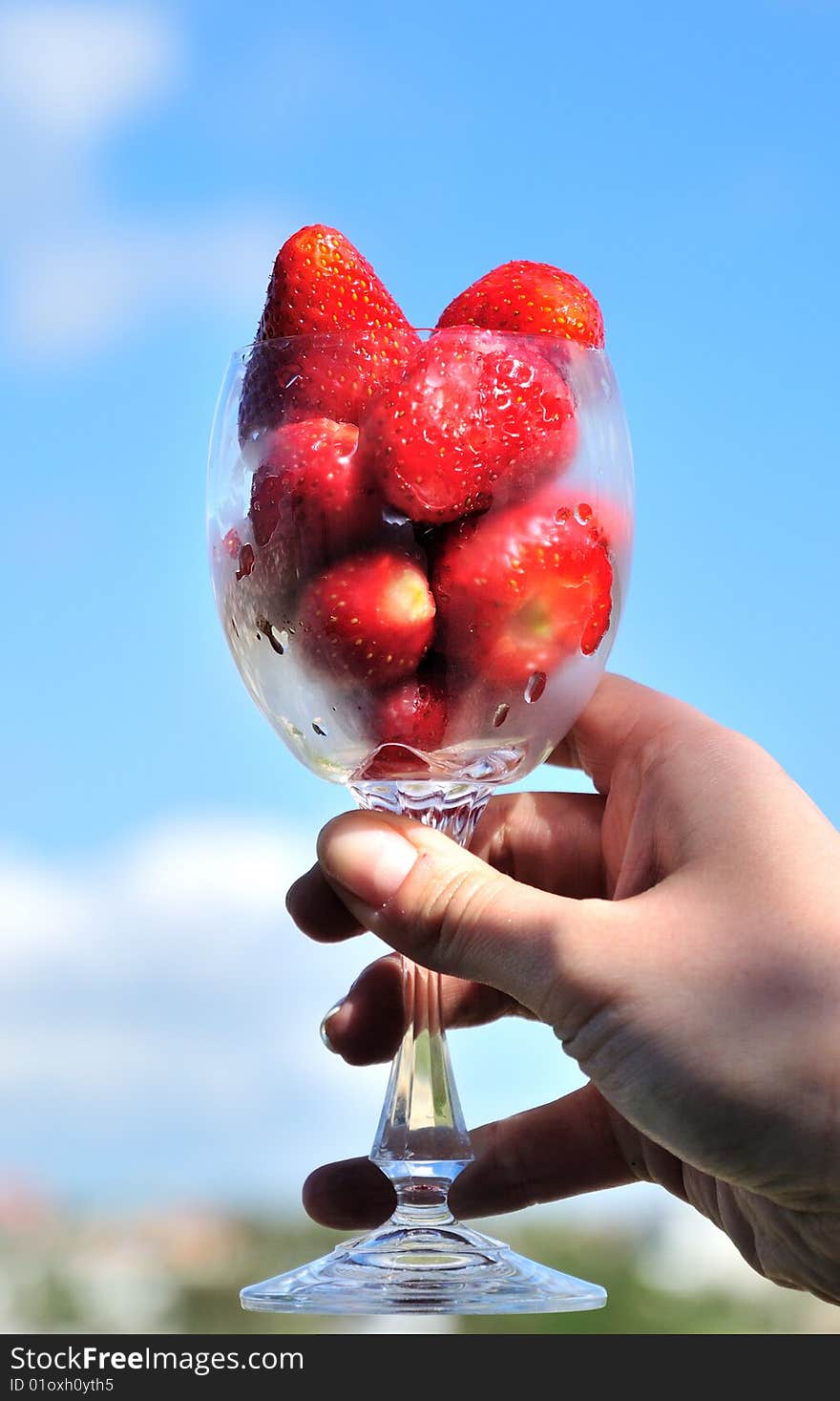 Fresh, sweet strawberry in glass over blue sky