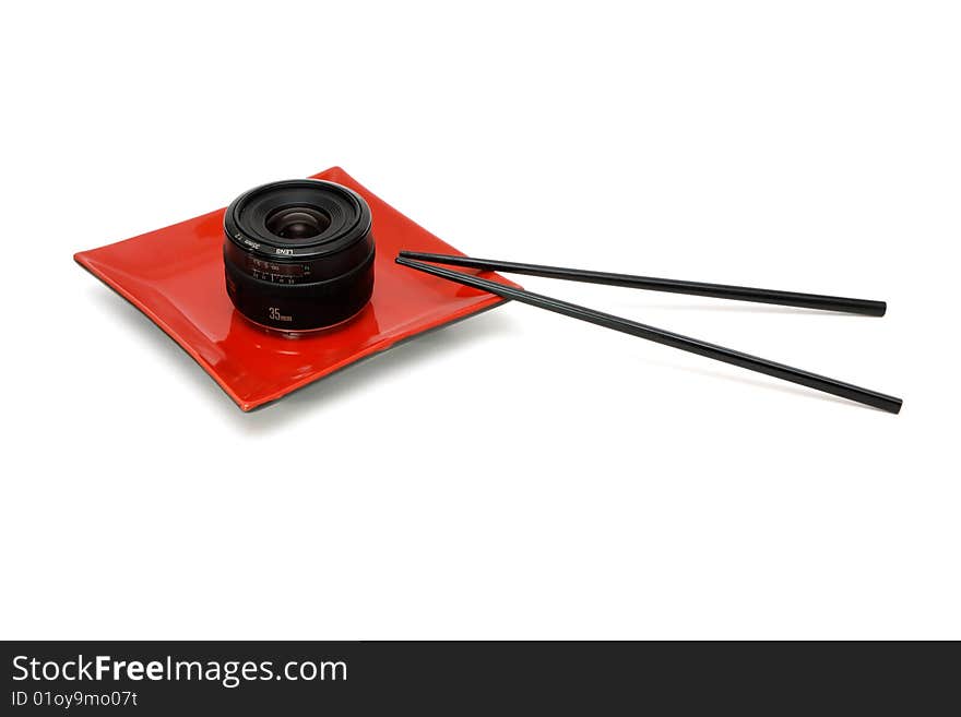 Objective lens on square red oriental plate with chopsticks isolated. Objective lens on square red oriental plate with chopsticks isolated