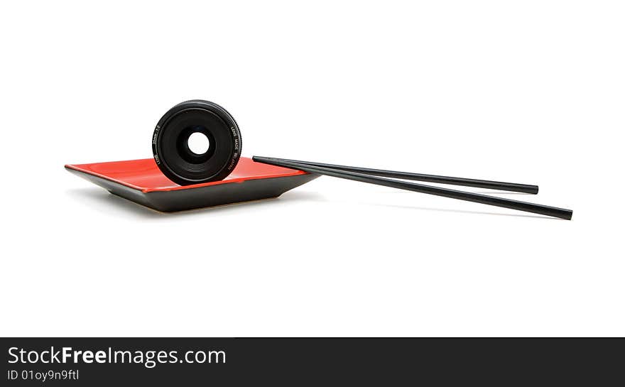 Objective lens on square red oriental plate with chopsticks isolated. Objective lens on square red oriental plate with chopsticks isolated