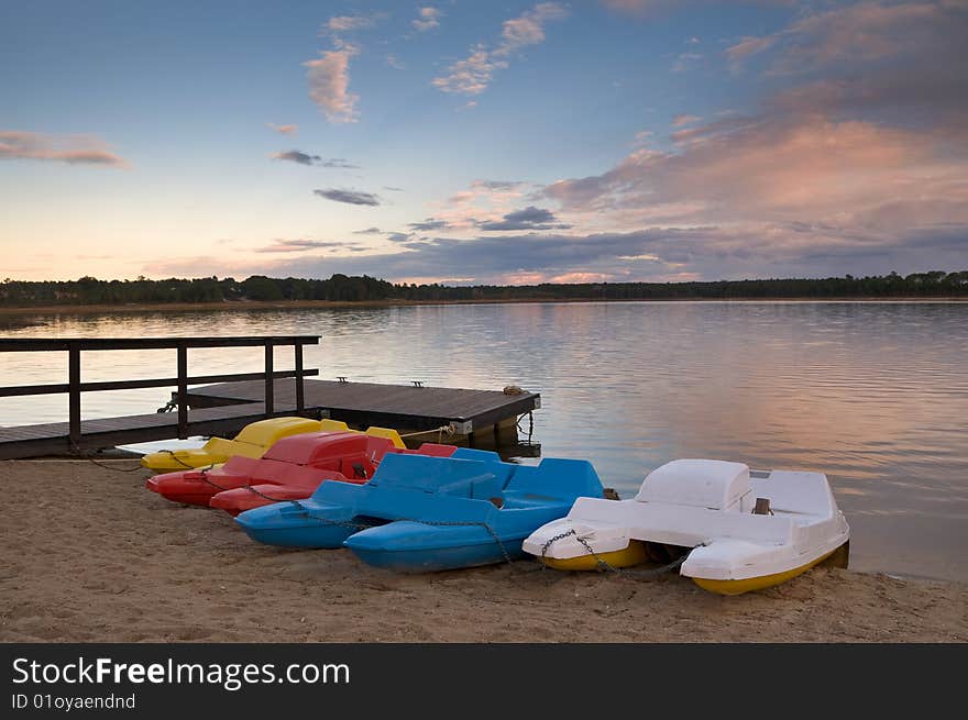 Pedal boats of various colors lined up at lake bank