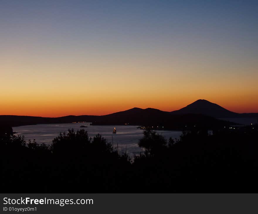 Sunset over city Mali Losinj in Croatia. Silhouette of mountains beautiful color palette. Sunset over city Mali Losinj in Croatia. Silhouette of mountains beautiful color palette.