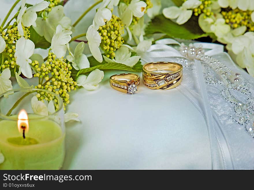 Wedding rings on bridal pillow with candle. Wedding rings on bridal pillow with candle.