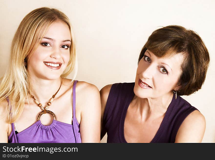 Beautiful mother and daughter against a light background