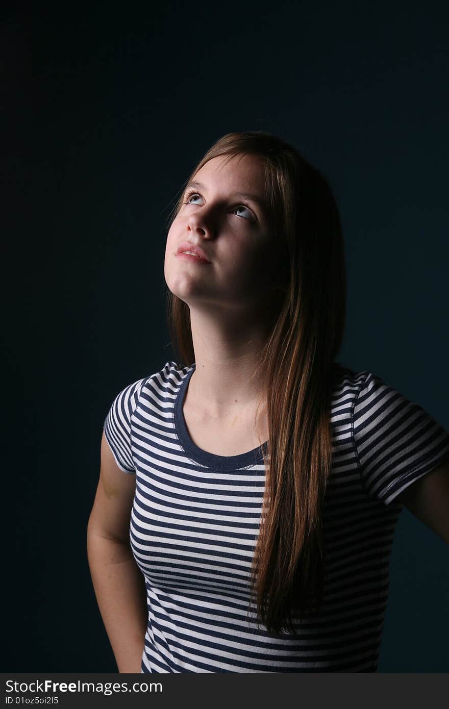 Pretty teenage girl with long hair and a striped shirt looking up and away