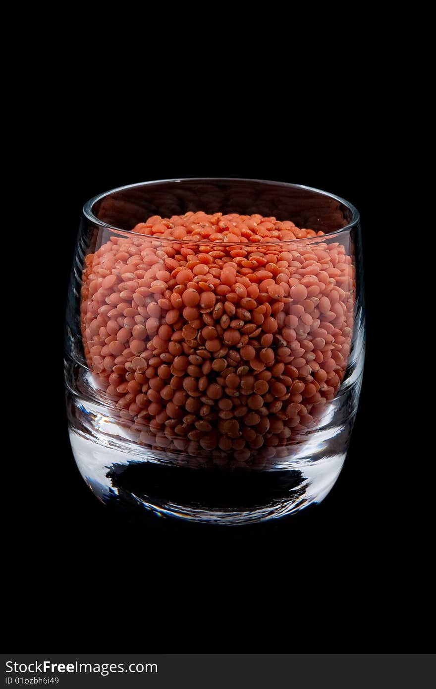 Red lentils in glass, black background