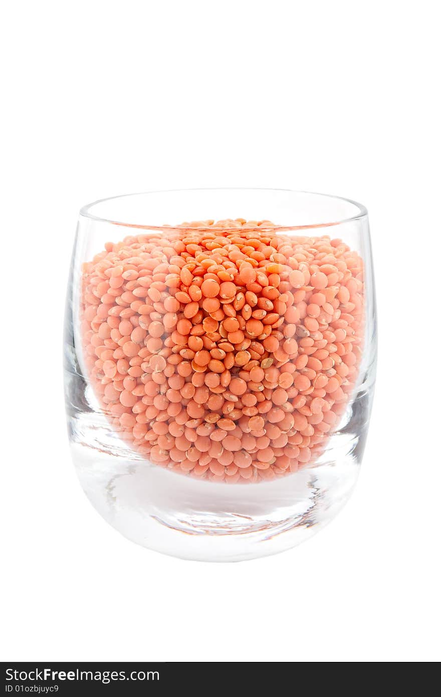 Red lentils in glass, white background