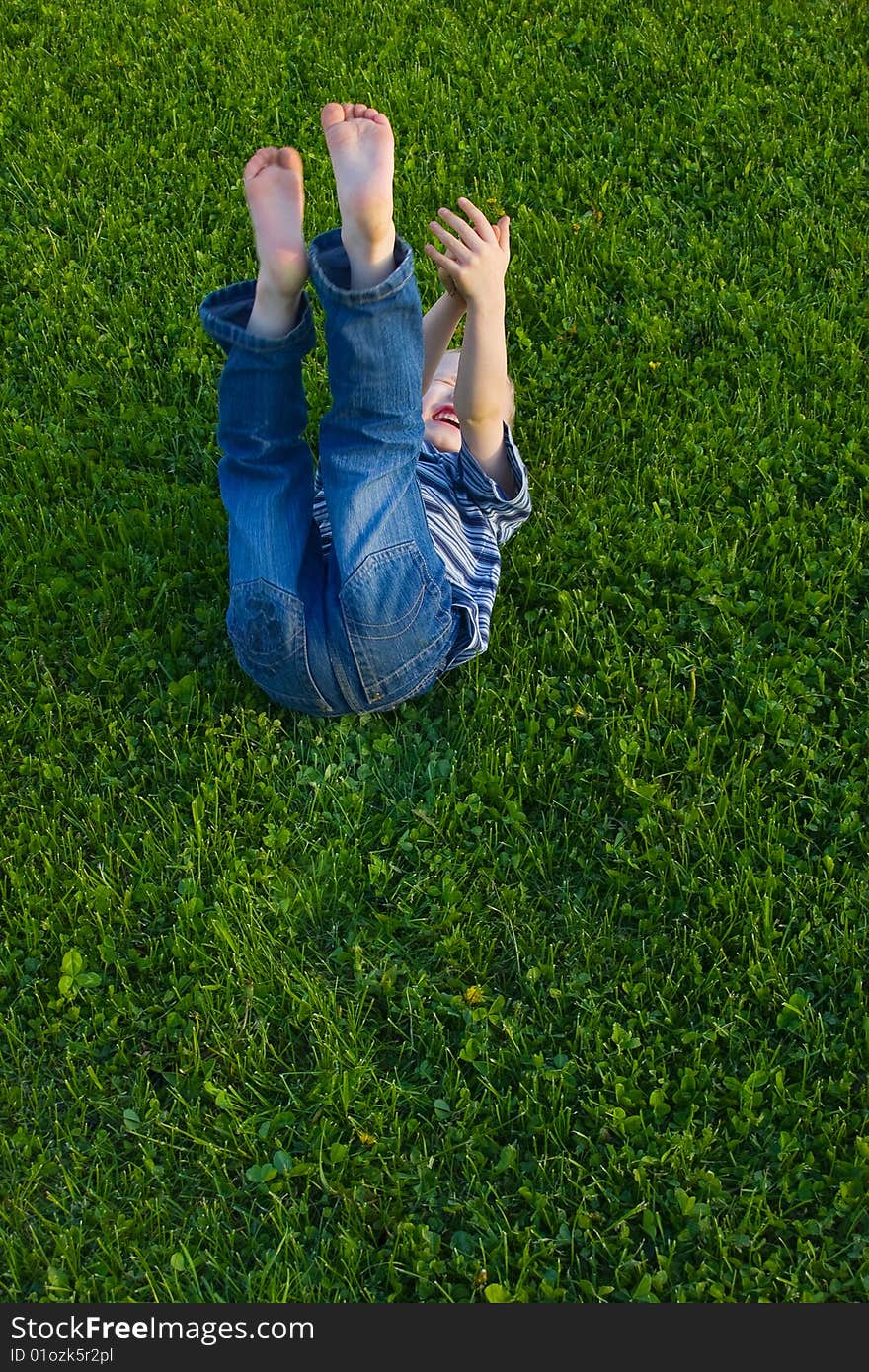 The four-year boy lies on a grass and laughing