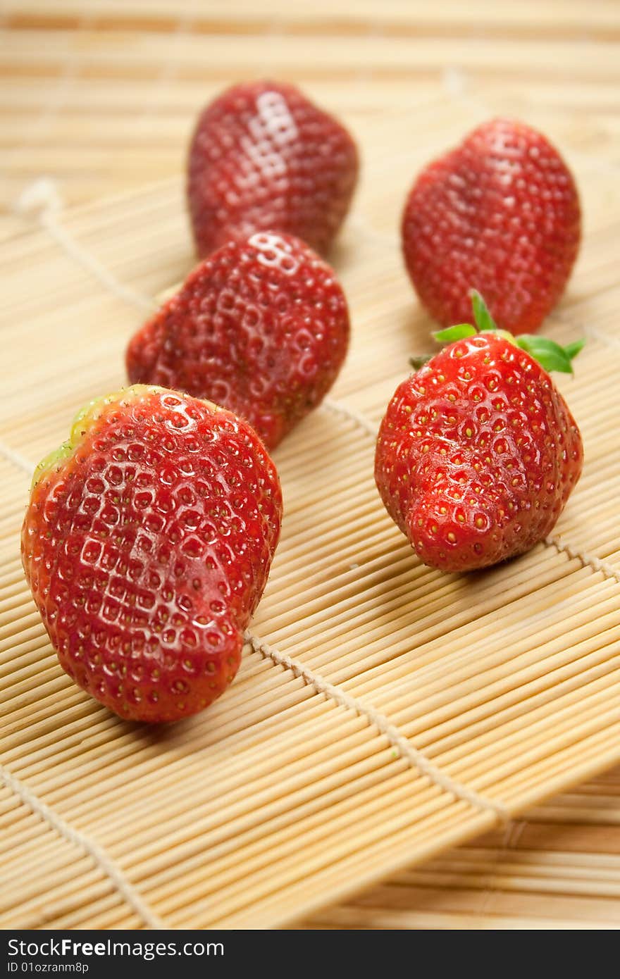 Fresh strawberries in rows on a bamboo mat