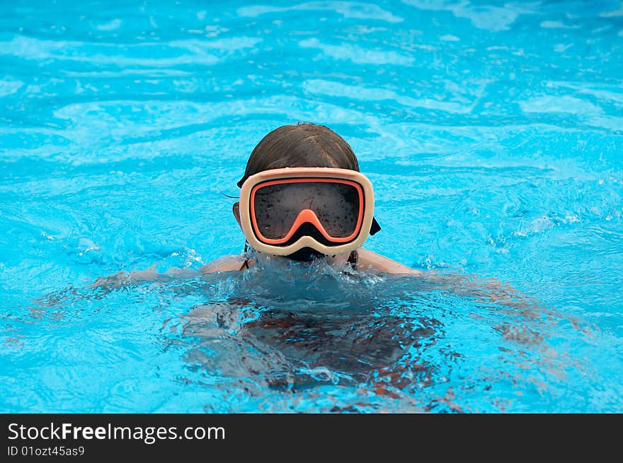 A young boy in pool with goggles on. A young boy in pool with goggles on