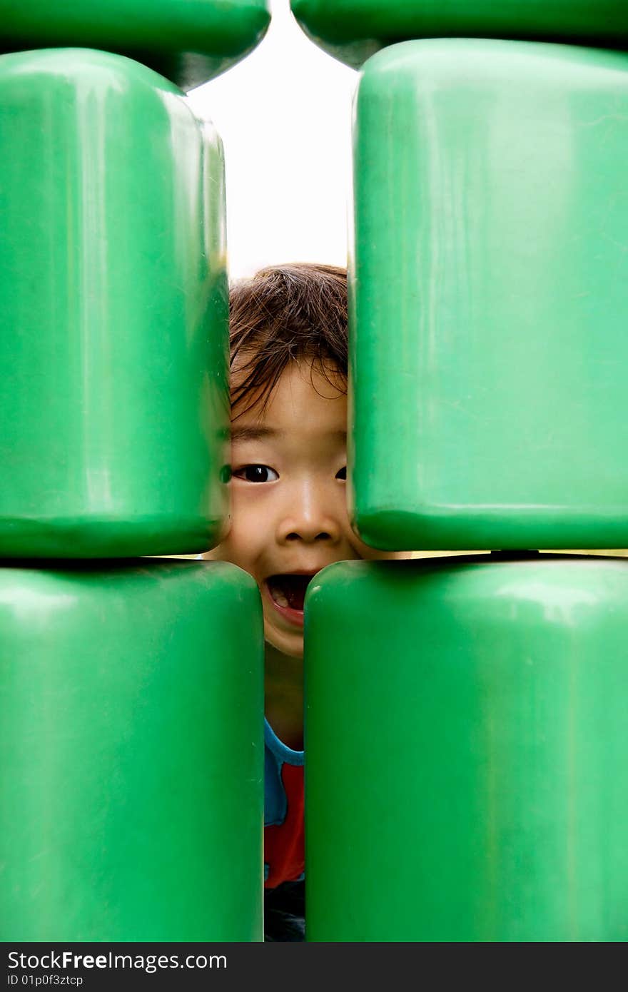 Picture of a little chinese boy hiding behind a big toy in a funfair. Picture of a little chinese boy hiding behind a big toy in a funfair