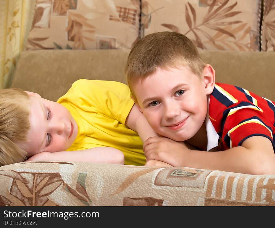 Portrait of two boys laying on a sofa of the house