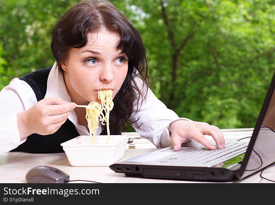 Young girl eats noodles and looks in the monitor. Young girl eats noodles and looks in the monitor