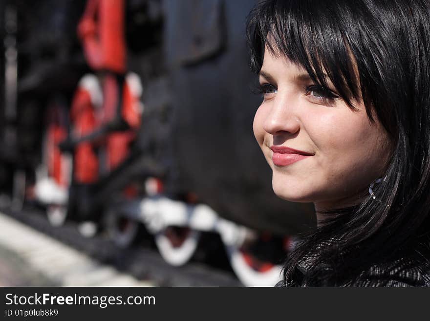 Portrait of the girl on a background of wheels of a steam locomotive. Portrait of the girl on a background of wheels of a steam locomotive