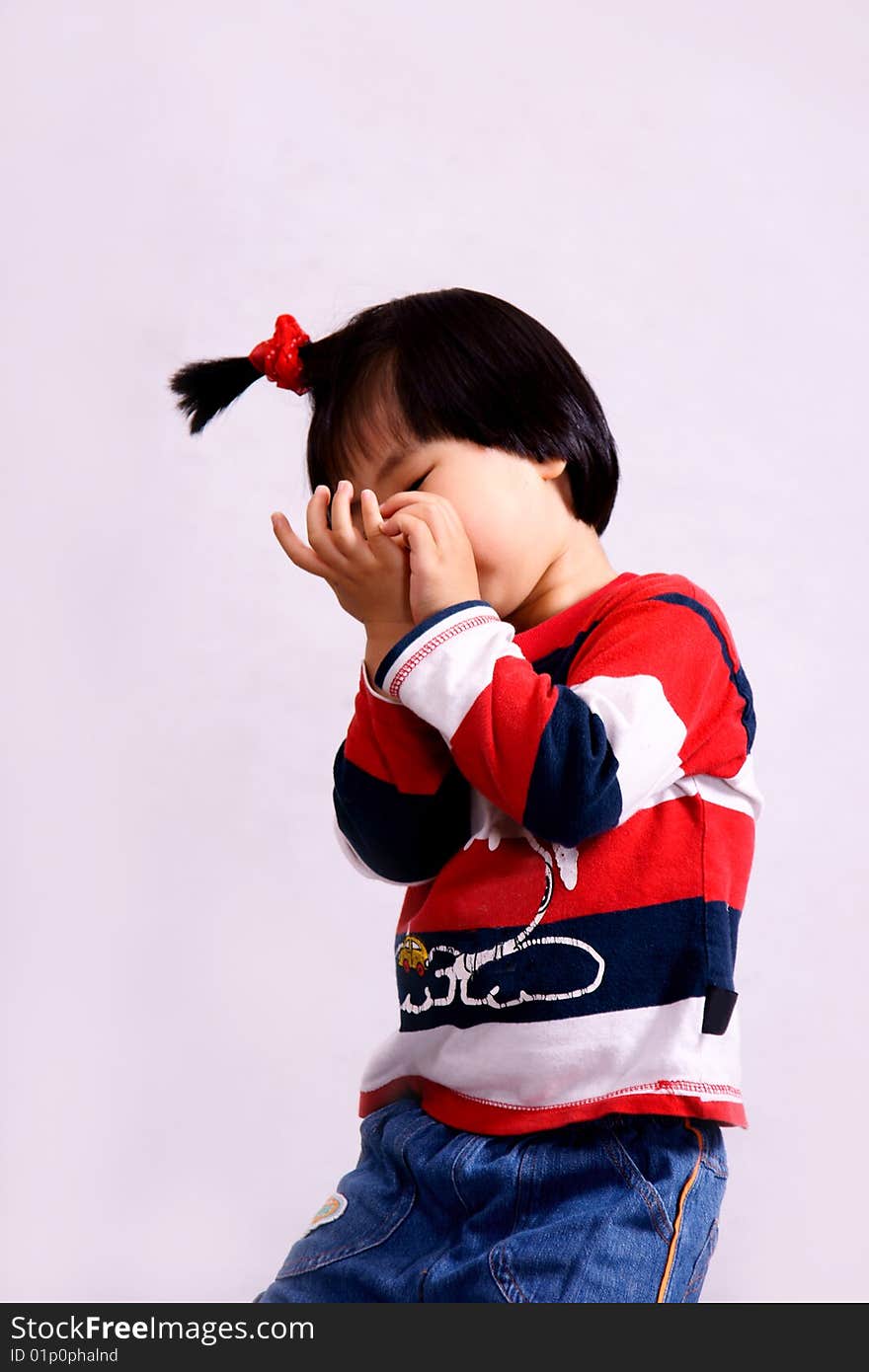 Picture of a little chinese girl with pigtail hiding face with hands