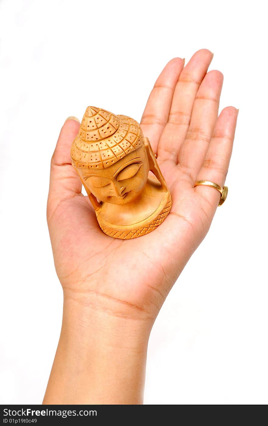 Female hand with wooden carving of buddha face isolated on white background. Female hand with wooden carving of buddha face isolated on white background