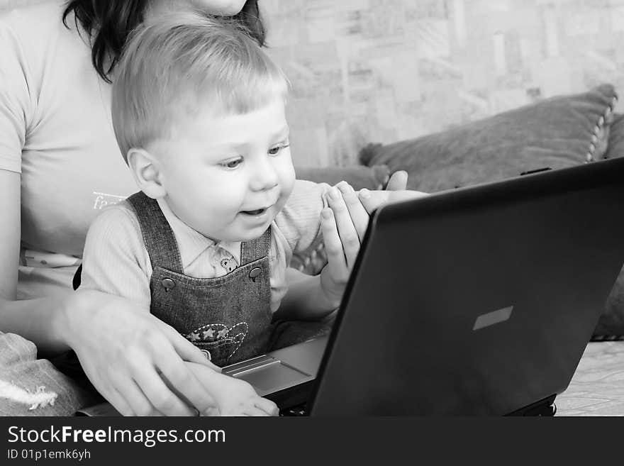 The small beautiful boy together with mum looks smiling on the screen laptop. The small beautiful boy together with mum looks smiling on the screen laptop