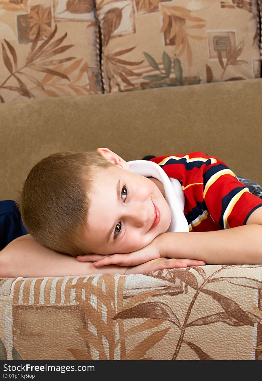 The little boy lays on a sofa of the house. The little boy lays on a sofa of the house