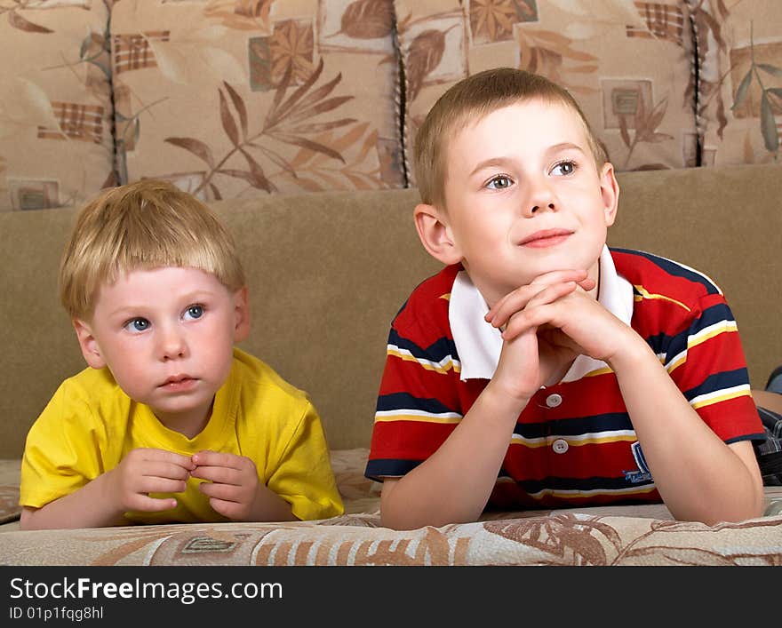 Portrait of two boys laying on a sofa of the house