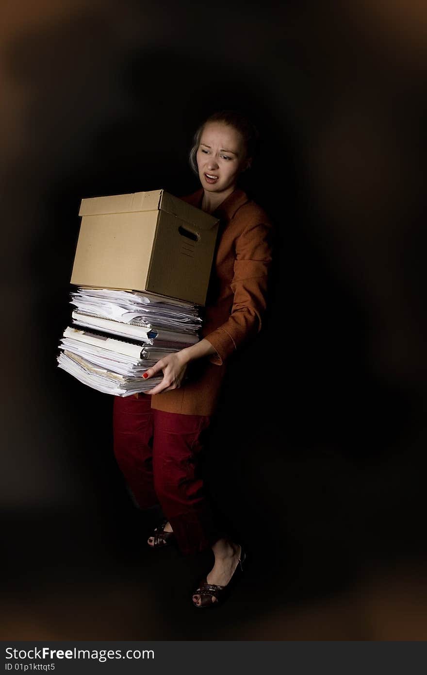 Young frustrated businesswoman with paper box - dark background