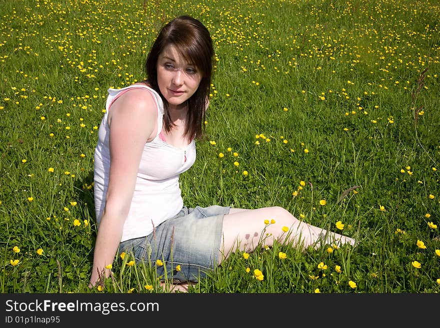 A woman sitting in a field. A woman sitting in a field