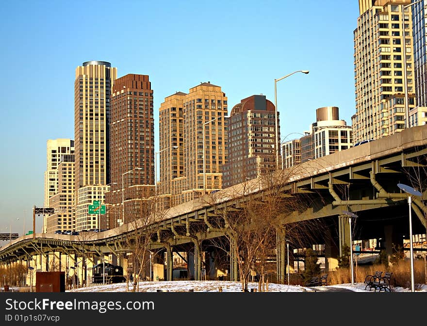 An urban landscape in NYC with a raised highway and tall residential and commercial buildings in the background.