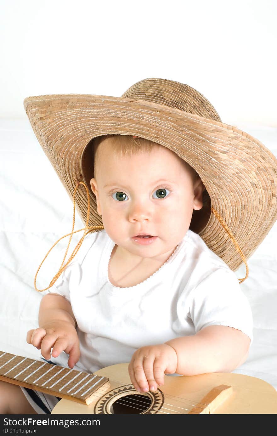 The little boy in a hat plays a guitar. The little boy in a hat plays a guitar