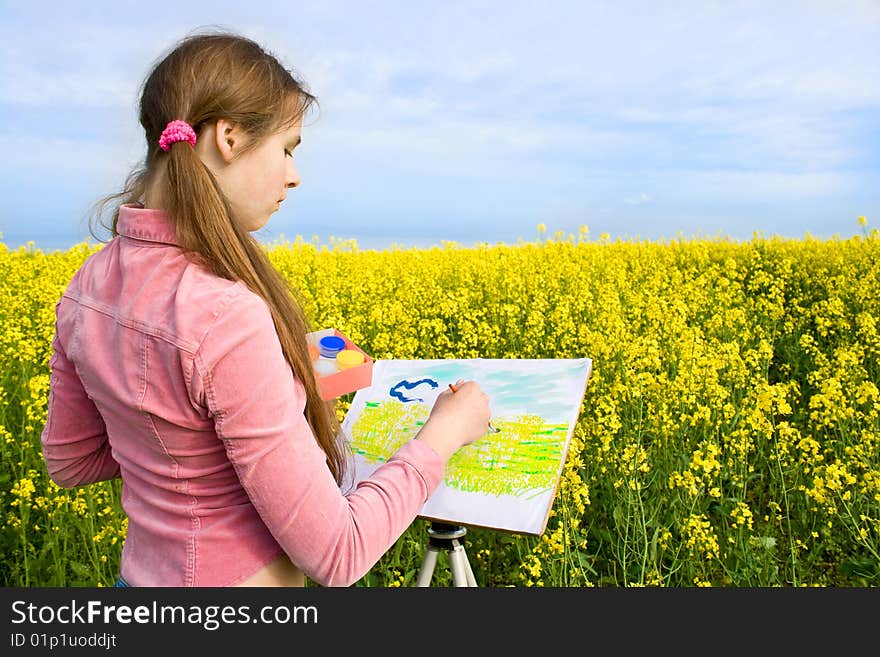 The girl with enthusiasm draws paints on a paper a landscape. The girl with enthusiasm draws paints on a paper a landscape.