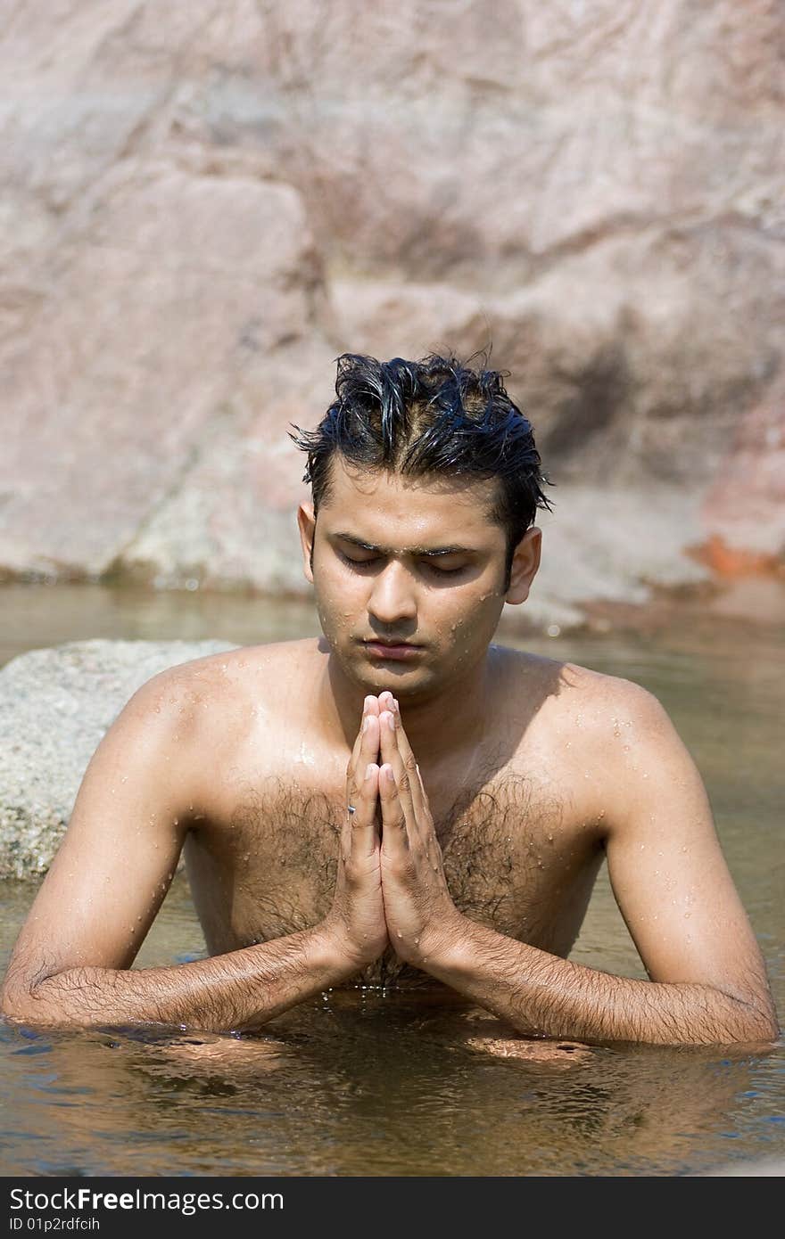 Man having yoga in water between stones