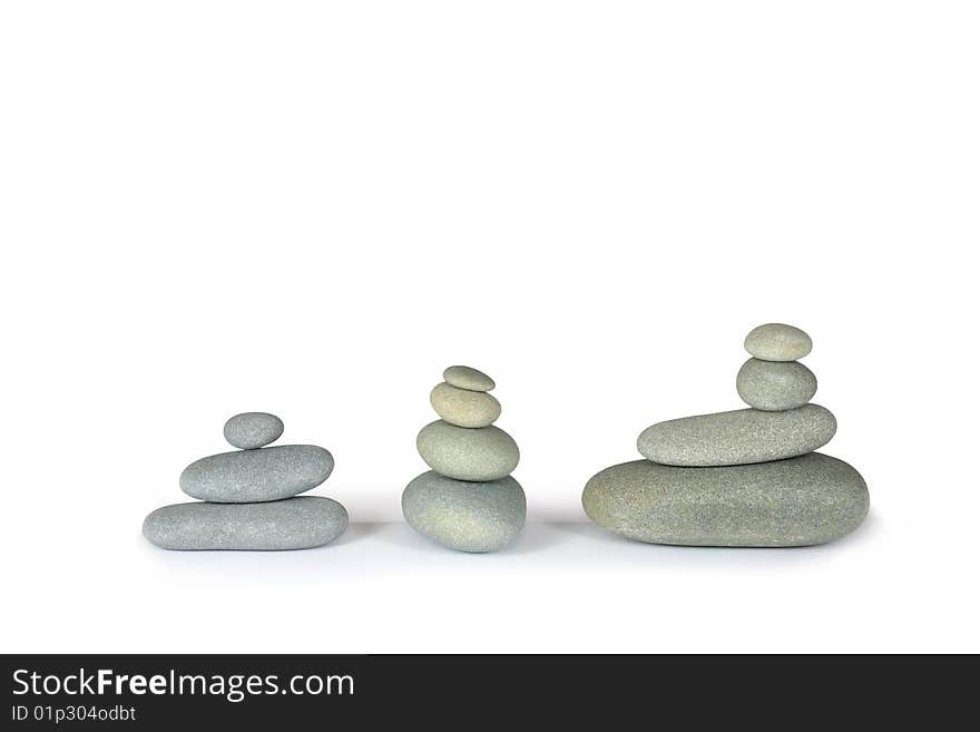 Three stacks of balanced grey stone pebbles, over white background.