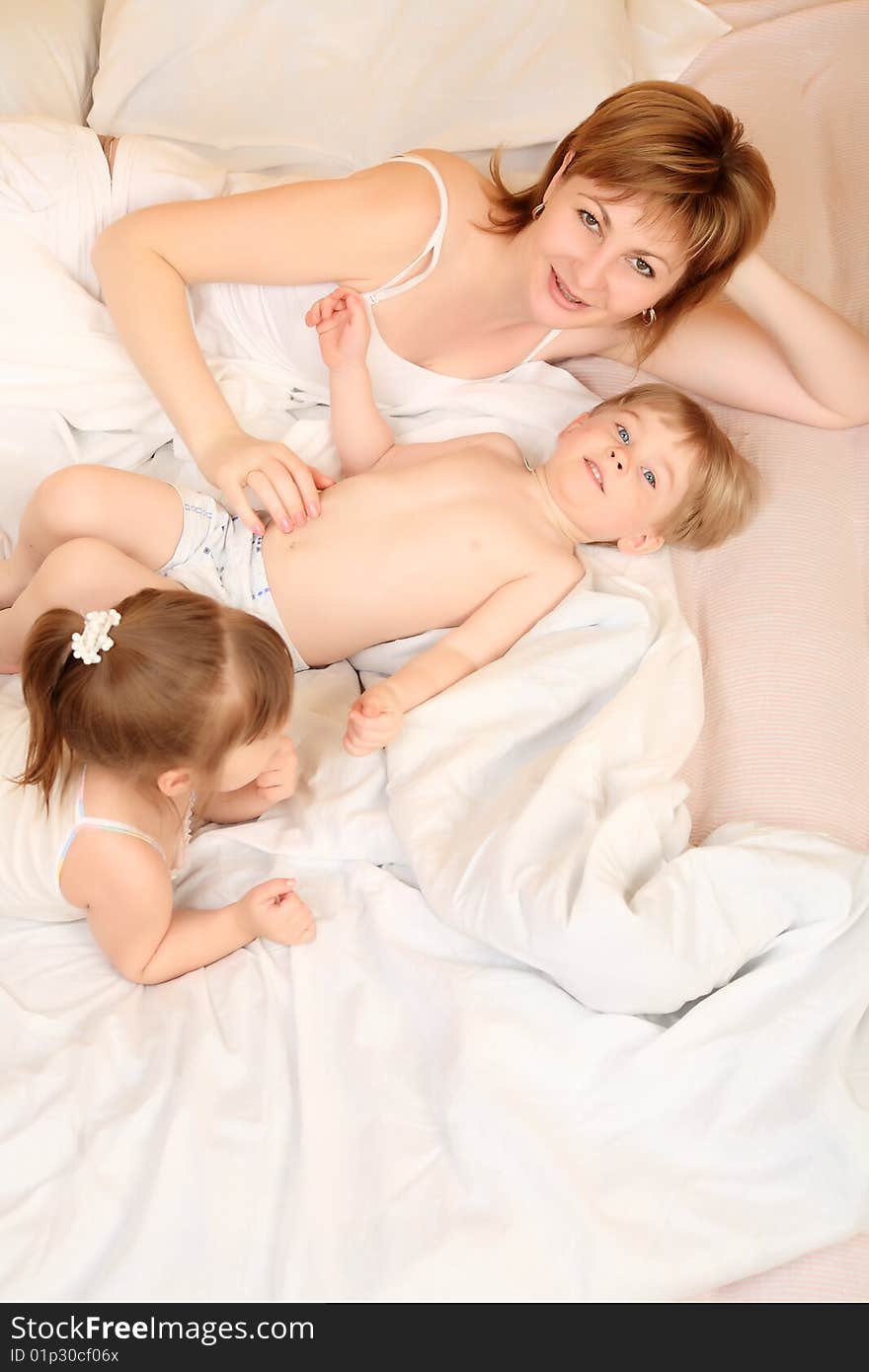 Portrait of a happy mother with her daughter and son  in a bedroom. Portrait of a happy mother with her daughter and son  in a bedroom.