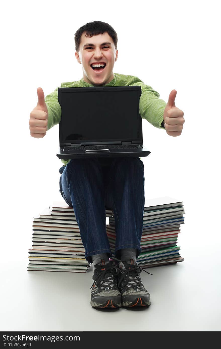 Portrait of a young man sitting on books with a laptop. Theme: education career, success. Portrait of a young man sitting on books with a laptop. Theme: education career, success.