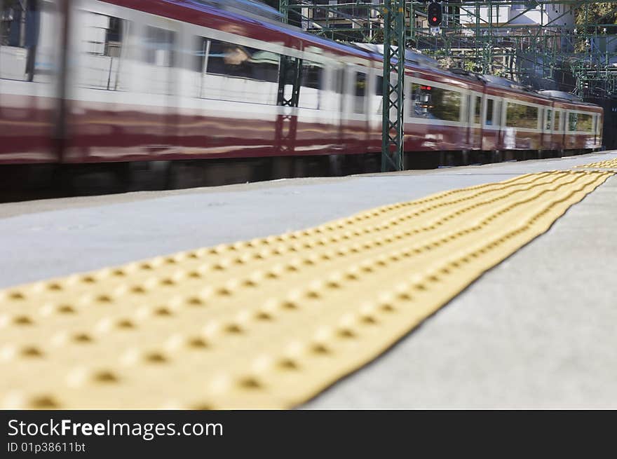 A red moving train at a train station from ground level.