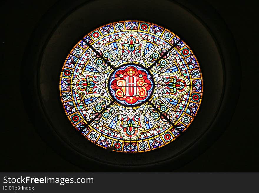 Circular window of a church. The transmitted light shows all the colors. Dark background. Place: Spanish church, Europe.