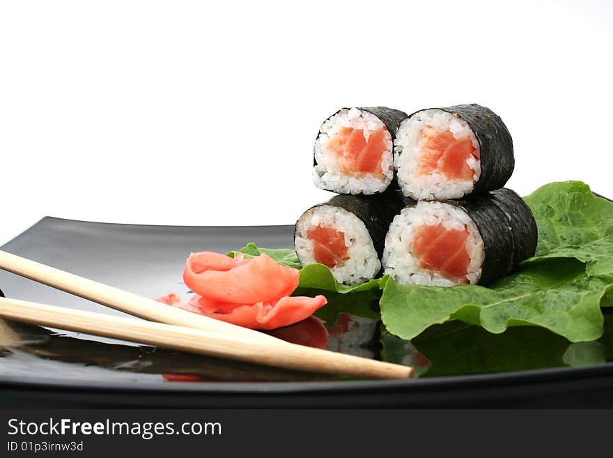 A sushi roll with ginger and stick on Japanese plate. A sushi roll with ginger and stick on Japanese plate