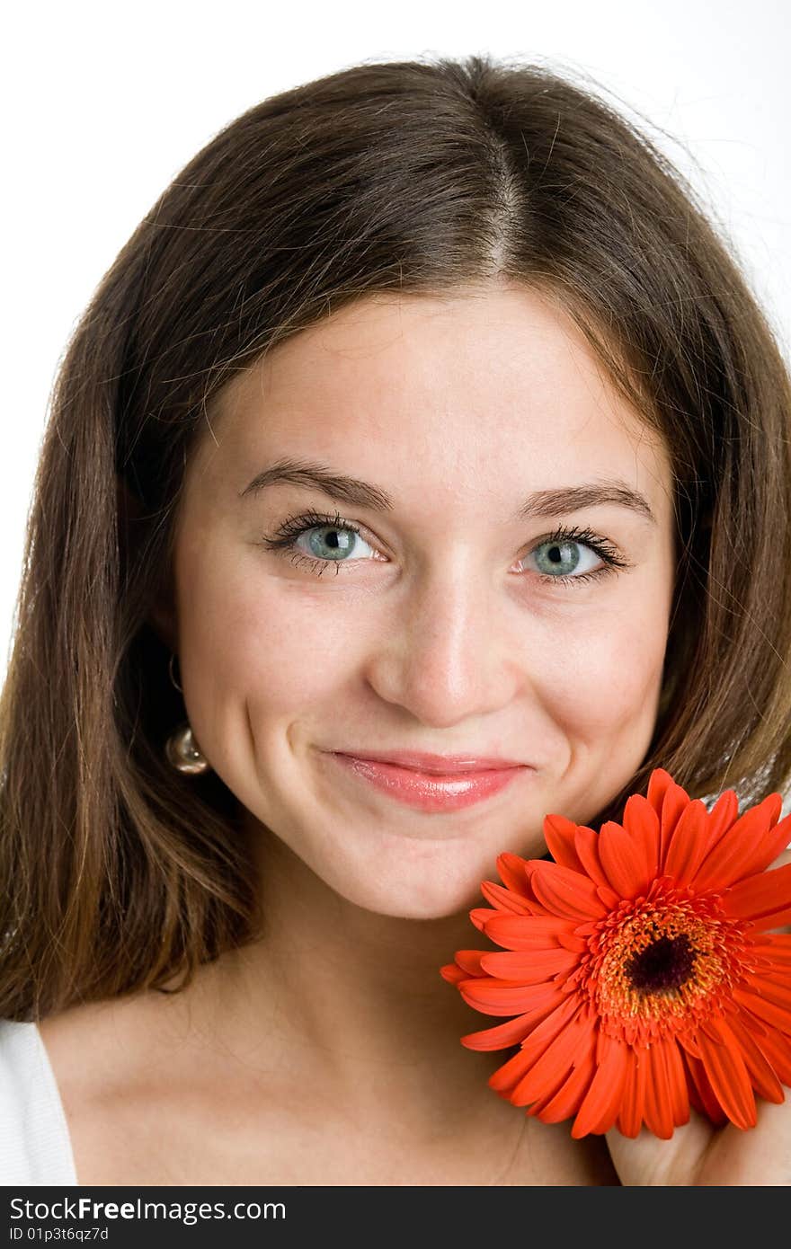 A smiling beautiful young woman in a white dress with a bright red flower near her face. A smiling beautiful young woman in a white dress with a bright red flower near her face