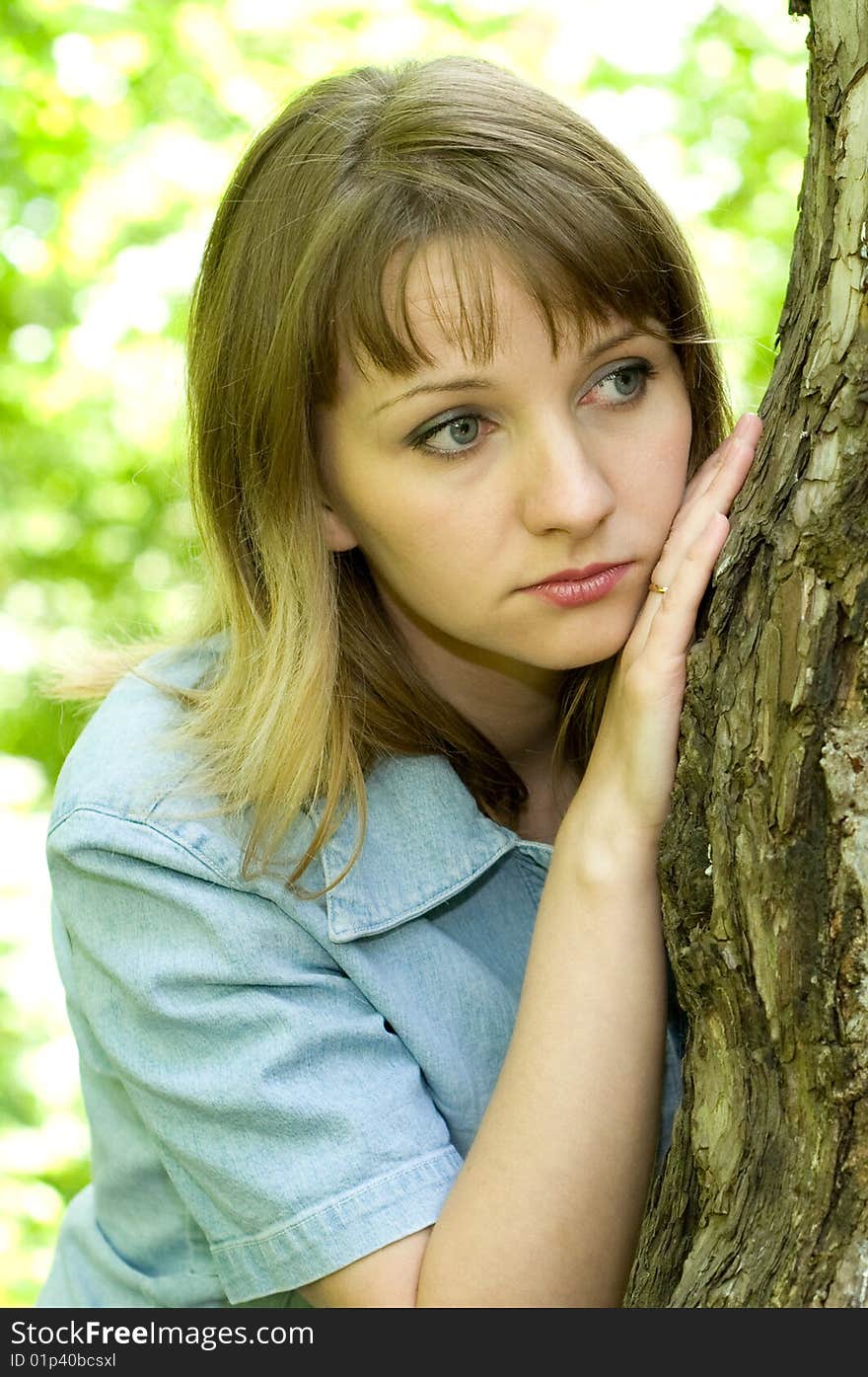 The beautiful girl in park to stand near an old tree. The beautiful girl in park to stand near an old tree