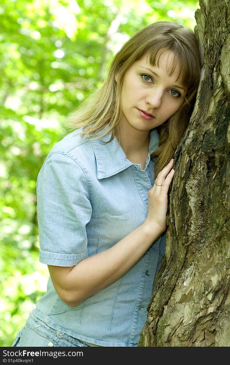 The beautiful girl in park to stand near an old tree. The beautiful girl in park to stand near an old tree