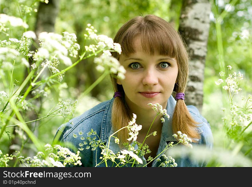 The beautiful girl in park sits on a green grass