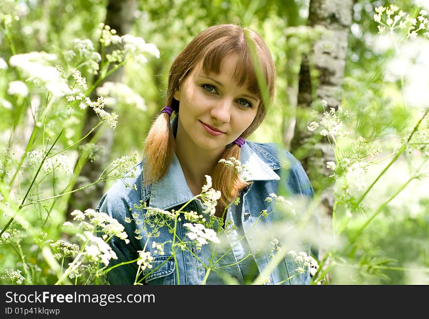 The beautiful girl in park sits on a green grass