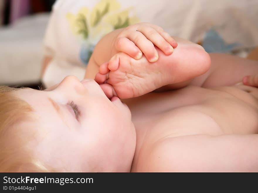 The little boy lays and holds a hand the leg. The little boy lays and holds a hand the leg