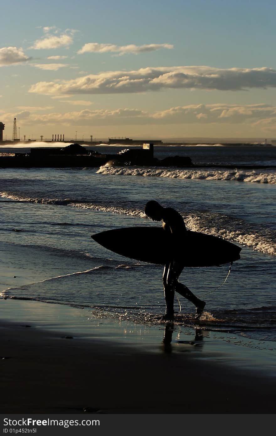 Surfer leaving the water at sunset. Surfer leaving the water at sunset