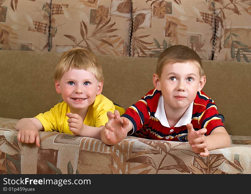 Portrait of two boys laying on a sofa of the house