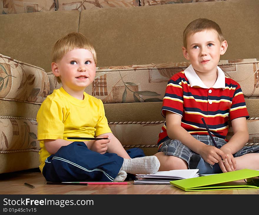 Two boys draw with paints sitting on floor