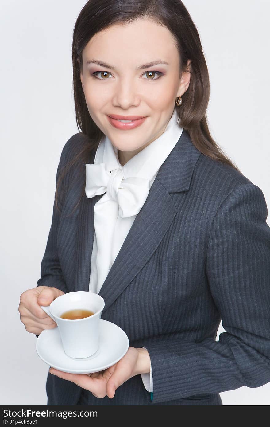 The woman in a business suit holds a cup with tea