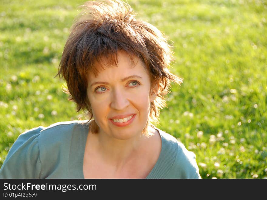 Woman sitting on green grass looking up to sky with good feeling. Woman sitting on green grass looking up to sky with good feeling